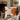 A white autumnal cushion with white and orange leaves and pumpkins sewn into the design, on a green chair